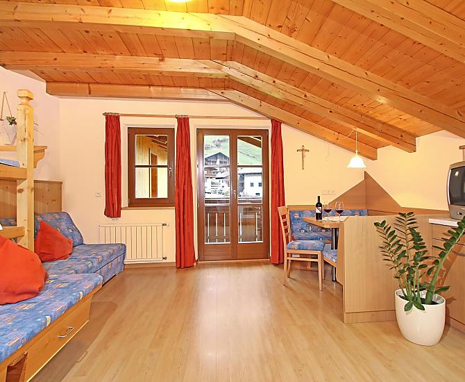 Wohnraum mit ausziehbarer Couch und traditionellem Bauernofen