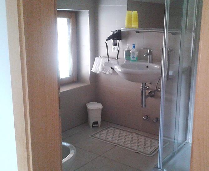 Bad mit Dusche und Duschkabine, Waschbecken, WC und Bidet.