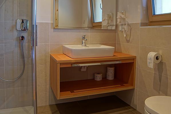 Badezimmer mit Dusche, WC, Bidet, Waschtisch, viel Ablagefläche und Föhn.