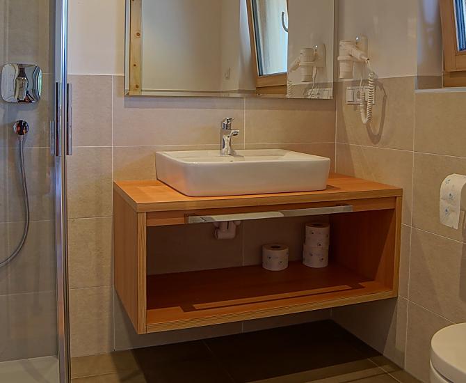 Badezimmer mit Dusche, WC, Bidet, Waschtisch, viel Ablagefläche und Föhn.