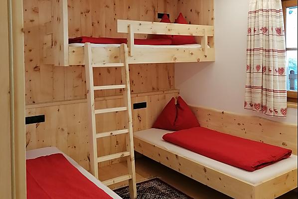 Zirbenholzschlafzimmer mit 2 Einzelbetten und einem Hochbett. Die Einzelbetten kann man zu einem Doppelbett zusammenschieben. 