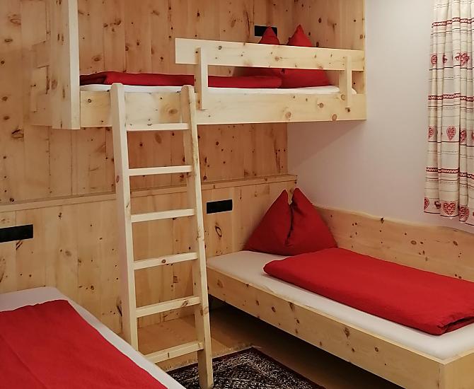 Zirbenholzschlafzimmer mit 2 Einzelbetten und einem Hochbett. Die Einzelbetten kann man zu einem Doppelbett zusammenschieben. 