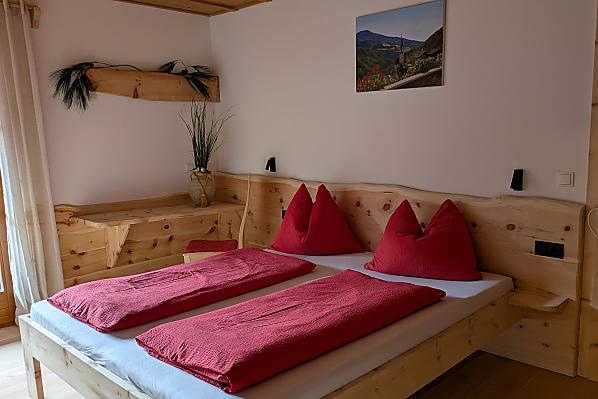 Das Doppelbettzimmer mit Naturholzboden verfügt über einen direkten Zugang zum Badezimmer und zum Balkon 