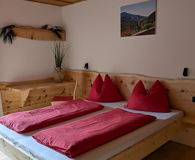 Das Doppelbettzimmer mit Naturholzboden verfügt über einen direkten Zugang zum Badezimmer und zum Balkon 