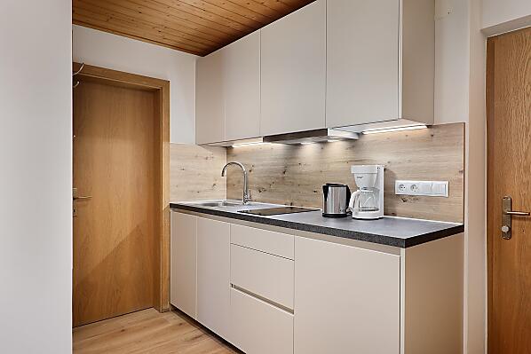 Küchenzeile mit Geschirrspüler, Kühlschrank mit Gefrierfach, Kaffeemaschine, Toaster, Mixer, Sat-TV, Herdplatte und Mikrowelle.