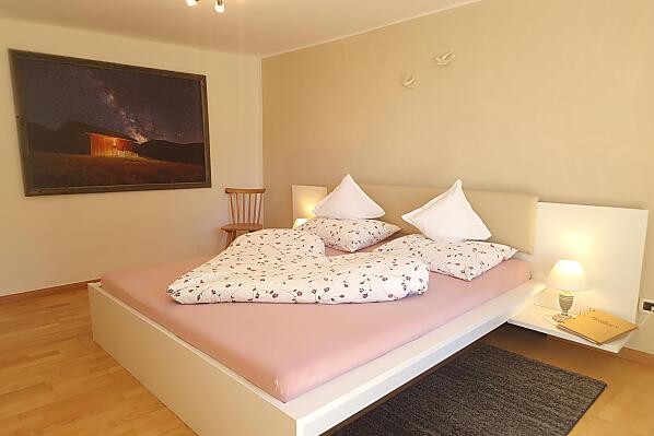 Gemütliches Schlafzimmer mit Zugang zum Balkon und Blick in den Bauerngarten und auf die Berge.